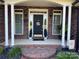 Inviting front porch with brick flooring, columns and a black front door at 115 Anson Dr, China Grove, NC 28023