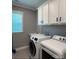 Bright laundry room with washer, dryer, and overhead cabinets at 2044 Sweet William Dr, Harrisburg, NC 28075