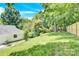 Large backyard with a sloped lawn and mature trees, offering privacy and natural beauty at 8433 Rittenhouse Cir, Charlotte, NC 28270