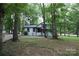 White house with black accents, nestled among lush trees at 310 Chaney St, Wingate, NC 28174