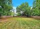 Large, fenced backyard with lush green grass and scattered autumn leaves at 919 Edgemont Ave, Belmont, NC 28012