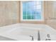 Bathroom with soaking tub, tile surround, and large window at 919 Edgemont Ave, Belmont, NC 28012