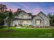 White farmhouse exterior illuminated at dusk, showcasing landscaping at 5811 Kristi Ln, Midland, NC 28107