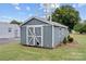 Gray storage shed with white trim and double doors in the backyard at 101 E Main St, Cleveland, NC 27013