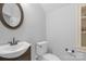 Small bathroom with white sink and toilet, brown vanity, and oval mirror at 15610 Youngblood Rd, Charlotte, NC 28278