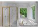 Spa-like bathroom featuring a soaking tub, walk-in shower, and wooded views at 15610 Youngblood Rd, Charlotte, NC 28278