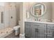 Modern bathroom with gray vanity, a walk-in shower, and round mirror at 514 Billy Howey Rd, Waxhaw, NC 28173