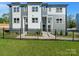 Modern 3-unit townhome building with gray and white siding, black fence, and landscaping at 8009 Elevate Ct, Charlotte, NC 28205
