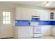 White kitchen cabinets, blue backsplash and tiled floor at 452 Mocksville Hwy, Statesville, NC 28625