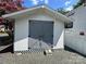White storage shed with gray doors and x-design accents at 113 Hummingbird Cir, New London, NC 28127