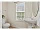 Simple bathroom with a toilet, sink, and window at 9622 Blossom Hill Dr, Huntersville, NC 28078