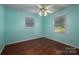 Light teal bedroom with wood floors, ceiling fan, and two windows at 1890 Rhyneland Rd, Lincolnton, NC 28092