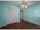 Light teal bedroom with wood floors, ceiling fan, and white louvered doors at 1890 Rhyneland Rd, Lincolnton, NC 28092
