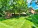 Large backyard with brick home, green grass, and mature trees at 1624 Chadmore Ln, Concord, NC 28027