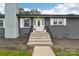 Gray brick front entrance with white door and concrete steps at 642 Fielding Rd, Charlotte, NC 28214