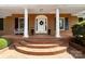 Brick front porch with columns, a white door, and potted plants at 3029 River Rd, Shelby, NC 28152