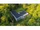 Aerial view showcasing a modern L-shaped home surrounded by lush greenery at 9224 Maggie Robinson Rd, Waxhaw, NC 28173