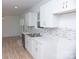 White kitchen with stainless steel appliances and light wood-look flooring at 830 Oakshire Cir, Charlotte, NC 28214