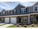 Townhouses with stone and gray siding, two-car garages, and landscaping at 5332 Cherrie Kate Ct # 1703, Stanley, NC 28164
