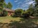 Landscaped backyard with a brick home and green space at 200 Linville Dr, Matthews, NC 28105