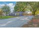 Ranch style home with gray exterior, gravel driveway, and mature trees at 335 Davidson Hwy, Concord, NC 28027