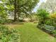 Large backyard with a grassy area, mature trees, and a garden at 11214 Sudbury Rd, Davidson, NC 28036