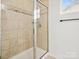 Beige tiled shower with a glass enclosure and a window at 4169 Oconnell St, Indian Trail, NC 28079