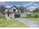 Modern farmhouse style home with a dark garage door and landscaping at 2305 Sanders Ave, Charlotte, NC 28216