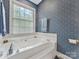 Bathroom with a large white jacuzzi tub, blue patterned wallpaper, and window at 6614 Alexander Hall Dr, Charlotte, NC 28270