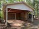 Carport with brown garage door and open sides, set against a wooded backdrop at 701 Whippoorwill Ln, Concord, NC 28025