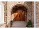 Elegant double wooden doors with arched entryway and brick accents at 4532 Lanstone Sw Ct, Concord, NC 28027