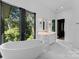 Bathroom with freestanding tub and marble flooring, with wooded views at 13702 Sage Thrasher Ln, Charlotte, NC 28278