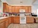Bright kitchen featuring oak cabinets, white appliances, and wood-look flooring at 104 Aberdeen Dr, Troutman, NC 28166