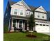 Two-story home with gray siding, stone accents, and a white garage door at 1077 Hearth Sw Ln, Concord, NC 28025