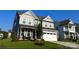 Two-story home with gray siding, stone accents, and a white garage door at 1077 Hearth Sw Ln, Concord, NC 28025