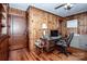 Home office with wood paneling, built-in shelving, and hardwood floors at 223 N Oak St, Statesville, NC 28677