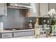 Modern gas cooktop with custom range hood and stylish backsplash at 1406 Hubert Graham Way, Tega Cay, SC 29708