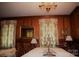 Elegant dining room featuring wood paneling, a chandelier, and floral curtains at 115 S Pearl St, Troy, NC 27371
