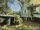 Side view of a small house with overgrown landscaping and a detached shed at 1115 Harrill St, Charlotte, NC 28205