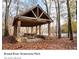 Rustic wooden pavilion with picnic tables, stone base, located in a wooded park setting at 110 Oak Crossing Dr, Shelby, NC 28152