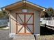 Tan colored storage shed with orange doors and a wooden ramp at 104 Cardinal Ave, New London, NC 28127