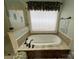 Oval soaking tub with neutral tile surround and window at 103 Berea Baptist Church Rd, Stanfield, NC 28163