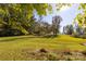 Large grassy lot with mature trees and distant road view at 130 Shiloh Rd, Troy, NC 27371