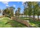 Lakefront backyard with stone wall, lush grass, and mature trees at 25566 Seagull Dr, Lancaster, SC 29720