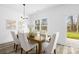 Bright dining area with a wooden table, white chairs, and large windows overlooking the backyard at 5311 Carden Dr, Charlotte, NC 28227