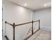 Upstairs hallway with wood railing and carpet flooring at 14905 Tamarack Dr, Charlotte, NC 28278