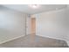 Well-lit bedroom with neutral walls, carpet flooring, and an interior door at 14905 Tamarack Dr, Charlotte, NC 28278