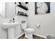 Stylish powder room with pedestal sink, toilet, and floating shelves at 303 Grove Gate Ln, Indian Trail, NC 28079