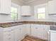 White kitchen cabinets, tile backsplash, and light wood floors at 1411 Lineberger Ave, Gastonia, NC 28052