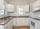White kitchen cabinets, tile backsplash, and light wood floors at 1411 Lineberger Ave, Gastonia, NC 28052